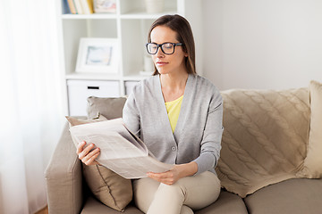 Image showing happy woman reading newspaper at home