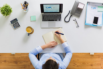 Image showing businesswoman writing to notebook at office