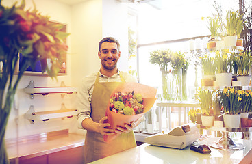 Image showing smiling florist man making bunch at flower shop