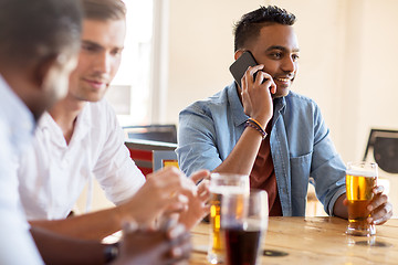 Image showing man calling on smartphone and drinking beer at bar