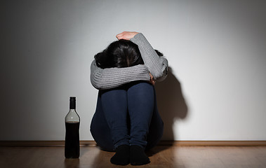Image showing woman with bottle of alcohol crying at home