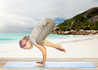 Image showing woman doing yoga in crane pose on beach