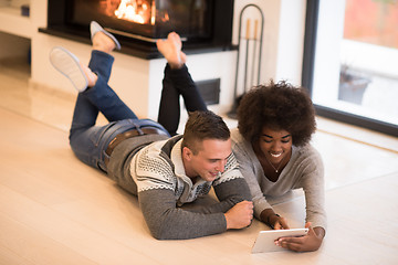 Image showing multiethnic couple using tablet computer on the floor