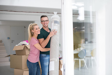 Image showing couple carrying a carpet moving in to new home