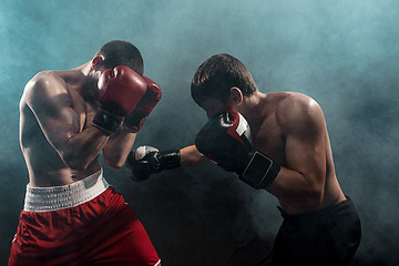 Image showing Two professional boxer boxing on black smoky background,