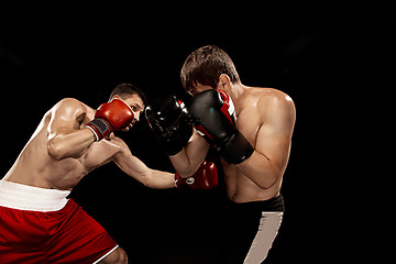 Image showing Two professional boxer boxing on black background,