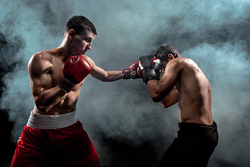 Image showing Two professional boxer boxing on black smoky background,