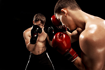 Image showing Two professional boxer boxing on black background,