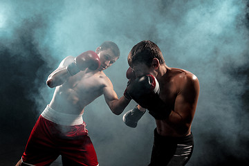 Image showing Two professional boxer boxing on black smoky background,