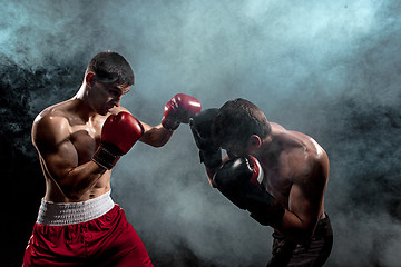 Image showing Two professional boxer boxing on black smoky background,