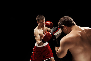 Image showing Two professional boxer boxing on black background,