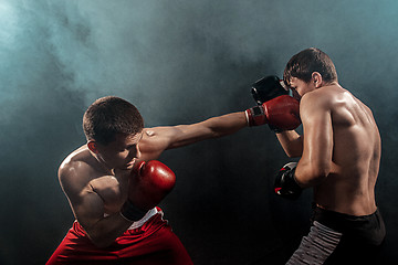 Image showing Two professional boxer boxing on black smoky background,