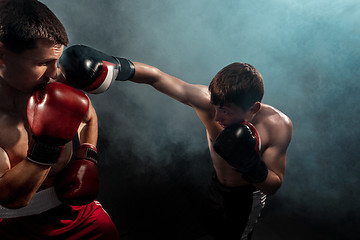 Image showing Two professional boxer boxing on black smoky background,