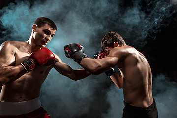 Image showing Two professional boxer boxing on black smoky background,