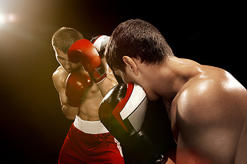 Image showing Two professional boxer boxing on black background,