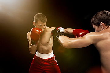 Image showing Two professional boxer boxing on black background,