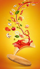 Image showing Tasty pizza and falling ingredients on orange background