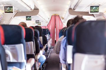 Image showing Interior of commercial airplane with passengers on seats during flight.