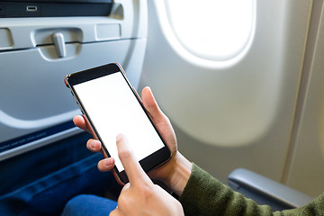 Image showing Holding digital mobile phone at airplane