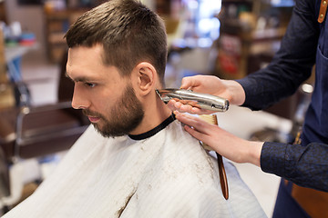 Image showing man and barber hands with trimmer cutting hair