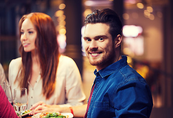 Image showing happy man with friends having dinner at restaurant