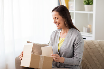 Image showing smiling woman opening cardboard box