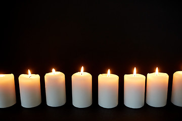 Image showing candles burning in darkness over black background