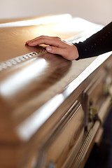 Image showing woman hand on coffin lid at funeral in church