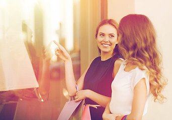 Image showing happy women with shopping bags at shop window