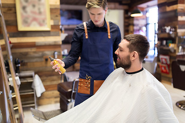 Image showing barber showing hair styling spray to male customer