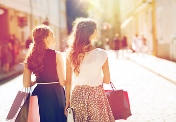 Image showing happy women with shopping bags walking in city 