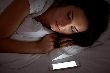 Image showing woman with smartphone sleeping in bed at night