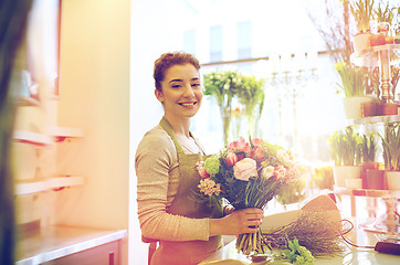 Image showing smiling florist woman making bunch at flower shop