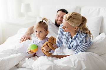 Image showing happy child with toys and parents in bed at home