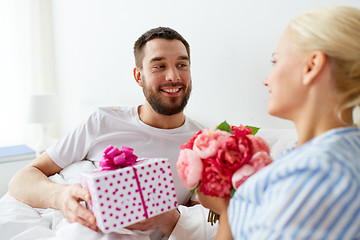 Image showing happy couple with gift box in bed at home