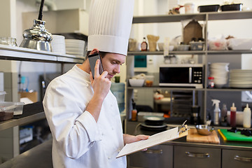 Image showing chef cook calling on smartphone at restaurant kitchen