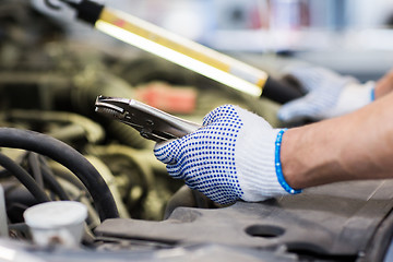 Image showing mechanic man with pliers repairing car at workshop