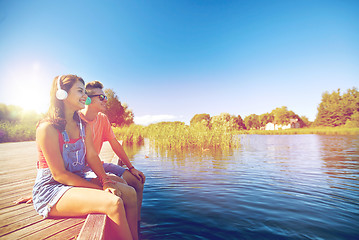 Image showing happy teenage couple with earphones on river berth