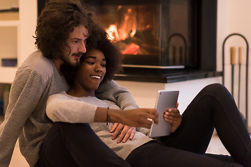 Image showing multiethnic couple using tablet computer on the floor