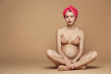 Image showing Young beautiful pregnant woman sitting on brown background