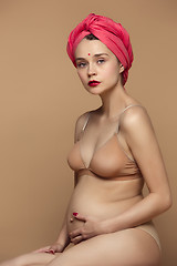 Image showing Young beautiful pregnant woman sitting on brown background