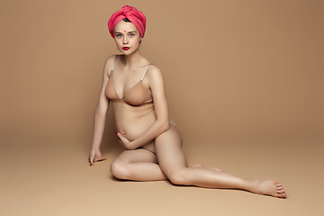 Image showing Young beautiful pregnant woman sitting on brown background