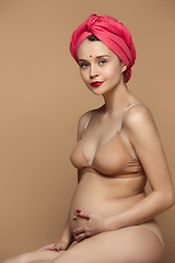 Image showing Young beautiful pregnant woman sitting on brown background