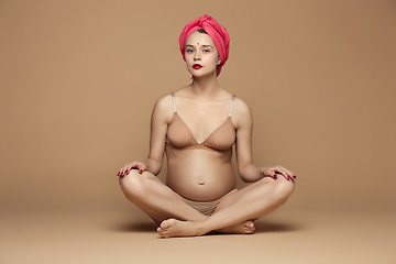 Image showing Young beautiful pregnant woman sitting on brown background