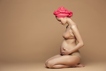 Image showing Young beautiful pregnant woman sitting on brown background