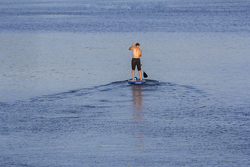 Image showing Man on Paddle Board paddling out to lake