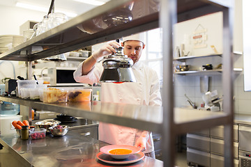 Image showing male chef heating food with lamp at  kitchen