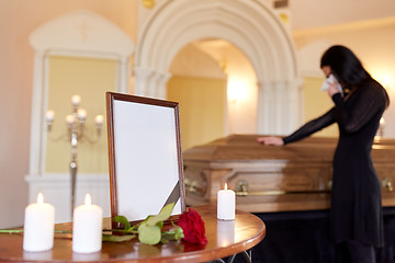 Image showing photo frame and woman crying at coffin at funeral