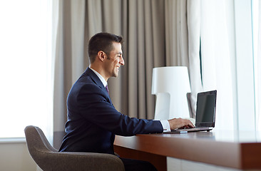 Image showing businessman typing on laptop at hotel room