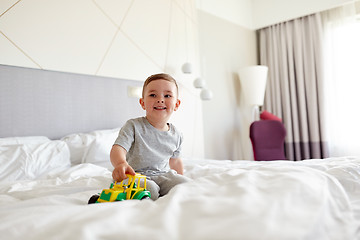 Image showing happy little boy with toy car on home or hotel bed